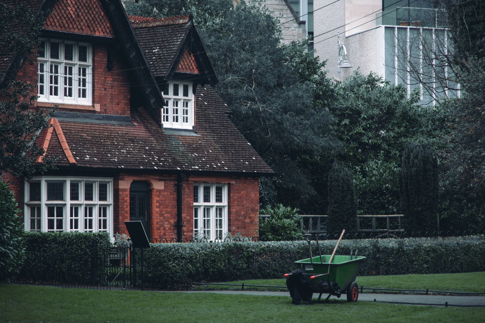 A red brick house with a green garden cart outside