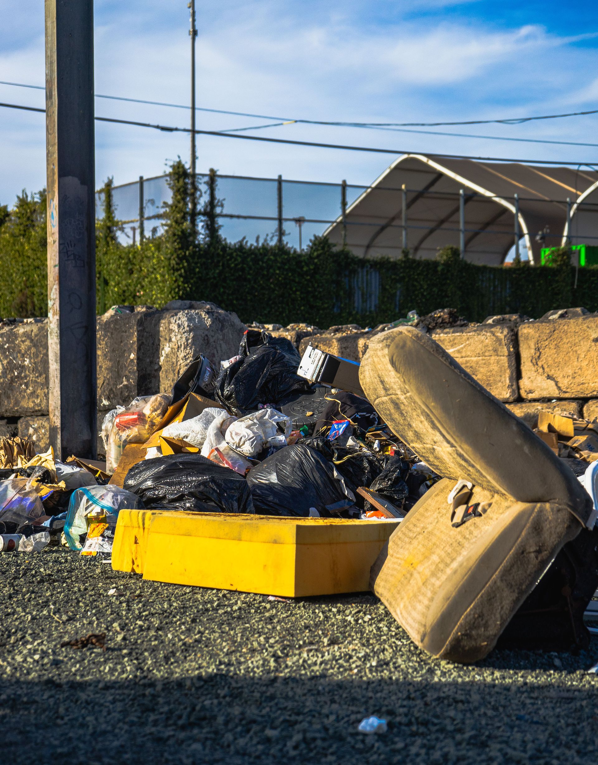 Outdoor scene of a garbage pile including a discarded mattress and various waste materials.
